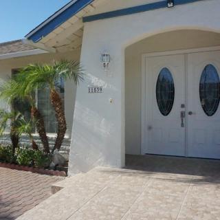 Front view of a house with an arched entryway and palm trees.