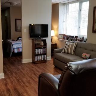 A cozy living room with a sofa, television, and hardwood flooring.