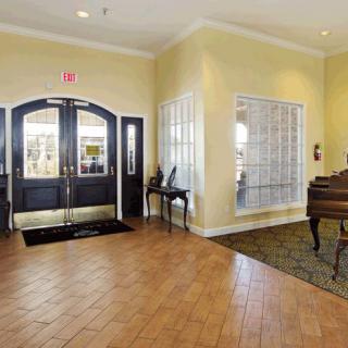 A spacious lobby area featuring a piano and double doors leading to the outside.