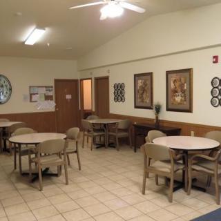An empty room with several tables and chairs, featuring wall decorations and a tile floor.