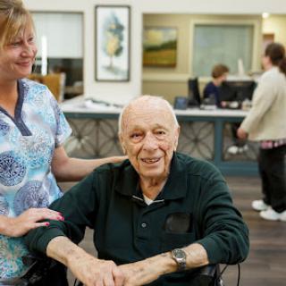 A caregiver shares a warm moment with an elderly resident at a nursing home.