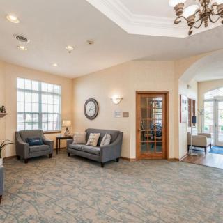 A cozy lobby featuring comfortable sofas, a chandelier, and large windows providing ample natural light.