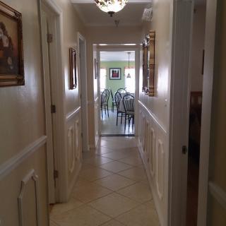 A view of a well-lit hallway leading to a dining area in a home.