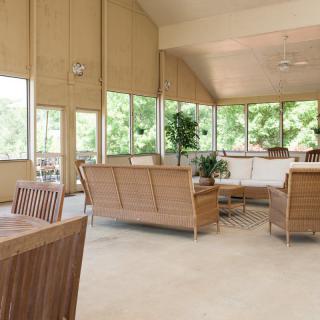 A modern living room featuring wood furniture and large windows, allowing ample natural light to fill the spacious area.