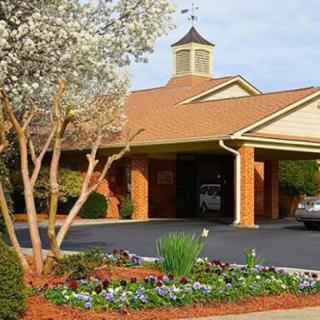 A landscaped entrance to a brick building with a driveway and floral arrangements.