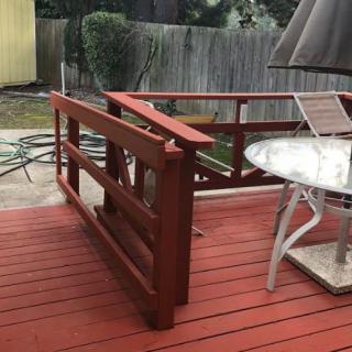 A wooden outdoor deck with red railing and a glass-topped patio table.