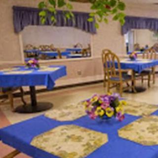 A cozy dining room with blue tablecloths and floral centerpieces.