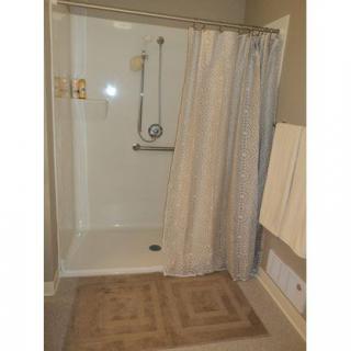 A bathroom with a walk-in shower, curtain, and towel rack.