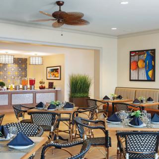 A well-decorated restaurant interior with neatly arranged tables and chairs, adorned with artwork and table settings.