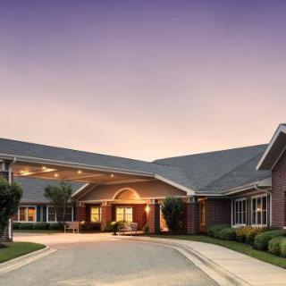 A welcoming building entrance at dusk with a well-maintained driveway and landscaping.