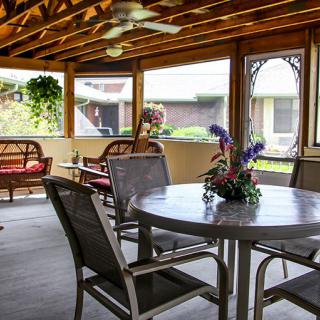 A cozy screened patio area with comfortable seating and a table adorned with a floral centerpiece.
