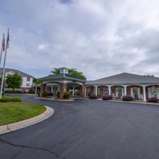A building with flags and a curved driveway under a cloudy sky.