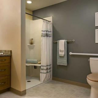 A modern bathroom with a shower, toilet, and towel rack.