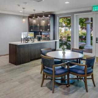A modern kitchen area featuring a round table with chairs, sophisticated lighting, and sleek cabinetry.