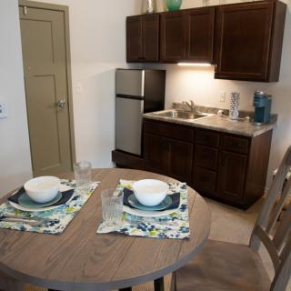 A small kitchen with a dining area featuring a round table set for two.