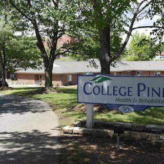 Entrance to College Pines, surrounded by trees and a clear pathway.