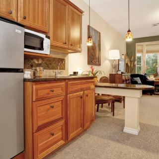 A cozy kitchen with wooden cabinets and stainless steel appliances, seamlessly opening into a comfortable living area.