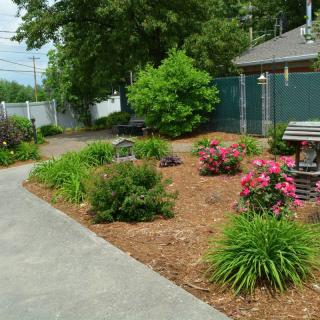 A beautifully landscaped garden with vibrant flowers and a paved pathway.