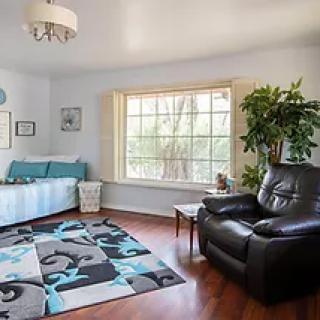 A cozy living room featuring a sofa, armchair, large window, and decorative carpet.