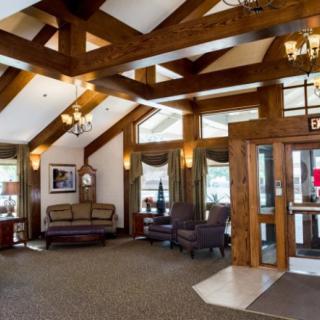 A cozy lobby featuring wooden beams, elegant chandeliers, and a comfortable seating area.
