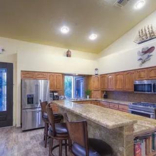 A modern kitchen featuring an island counter with bar stools, wood cabinetry, and stainless steel appliances.