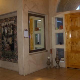 A hallway featuring a large mirror, artwork on the wall, and a wooden door.