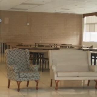 An empty room with a patterned armchair and a white sofa.
