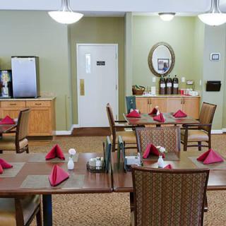 A neatly arranged dining area with tables set for service, featuring red napkins and classic decor.