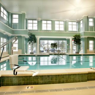 A serene indoor swimming pool area featuring ample natural light and modern design elements.