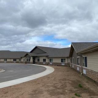 A newly constructed building under a cloudy sky with a surrounding parking area.