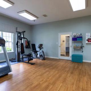 A clean and well-lit gym with exercise equipment including a treadmill and weights.