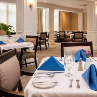 An elegantly set dining area with neatly arranged tables and blue napkins.