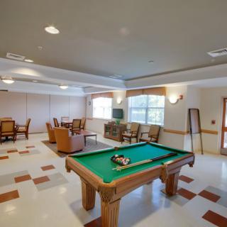 A recreation room featuring a pool table, comfortable seating, and a television.