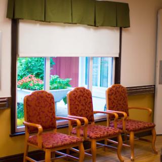 A cozy waiting area featuring three upholstered chairs and a view of greenery outside.