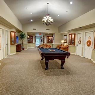 A spacious lobby area featuring a pool table, comfortable seating, and a decorative chandelier.