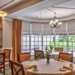 An elegant dining room with a round table, comfortable chairs, and a chandelier.