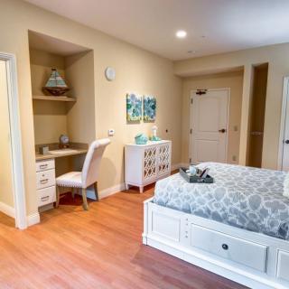 A modern bedroom with a cozy bed, desk, and chair on a wooden floor.
