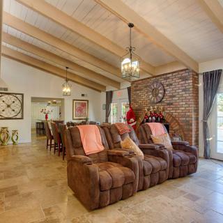 A cozy living room featuring recliner sofas and a brick fireplace, with exposed wooden beams and pendant lighting.