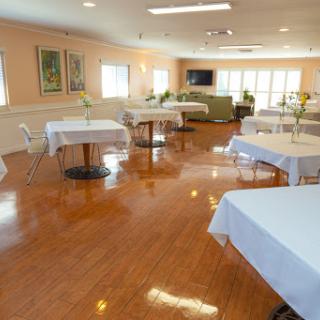 A well-lit indoor dining area featuring multiple tables dressed in white tablecloths, creating a clean and inviting atmosphere.