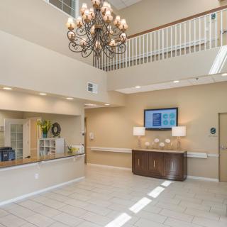 A spacious lobby with a chandelier, reception desk, and balcony.