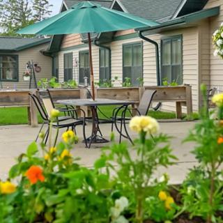 A serene garden patio with a table, chairs, and vibrant flowers in the foreground.