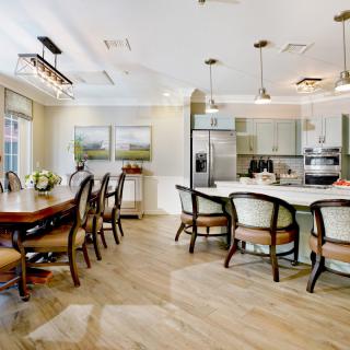 A modern kitchen and dining area featuring elegant furniture, wood flooring, and stylish lighting fixtures.