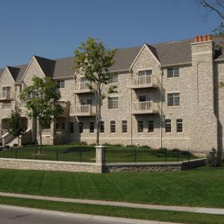 A modern residential apartment building set against a clear blue sky.