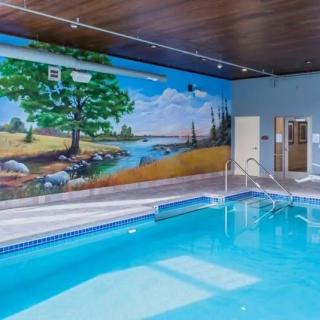 An indoor swimming pool with a vibrant mural of a scenic landscape on the wall.