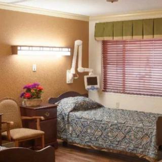 A hospital room with a bed, chair, and medical equipment.