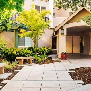 A welcoming entrance surrounded by lush landscaping and a paved pathway.