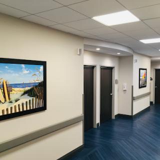 A well-lit hospital corridor featuring artwork on the walls and two doorways.