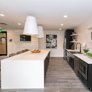 A modern kitchen with a large island, pendant lighting, and stainless steel appliances.