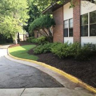 A well-maintained building exterior with a curving driveway and neatly landscaped greenery.