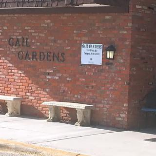 A brick building with benches outside and a sign on the wall.